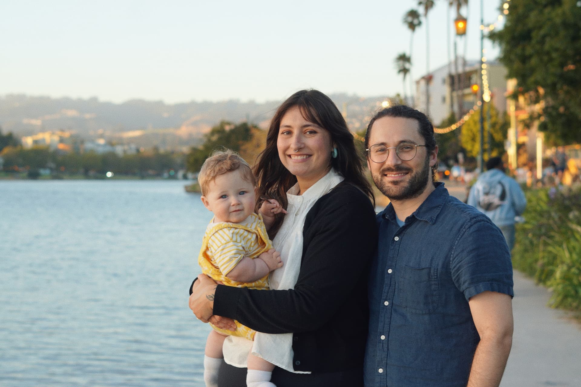 The Espicha-Blumenstein family smiling together beside the water at Lake Merritt at golden hour