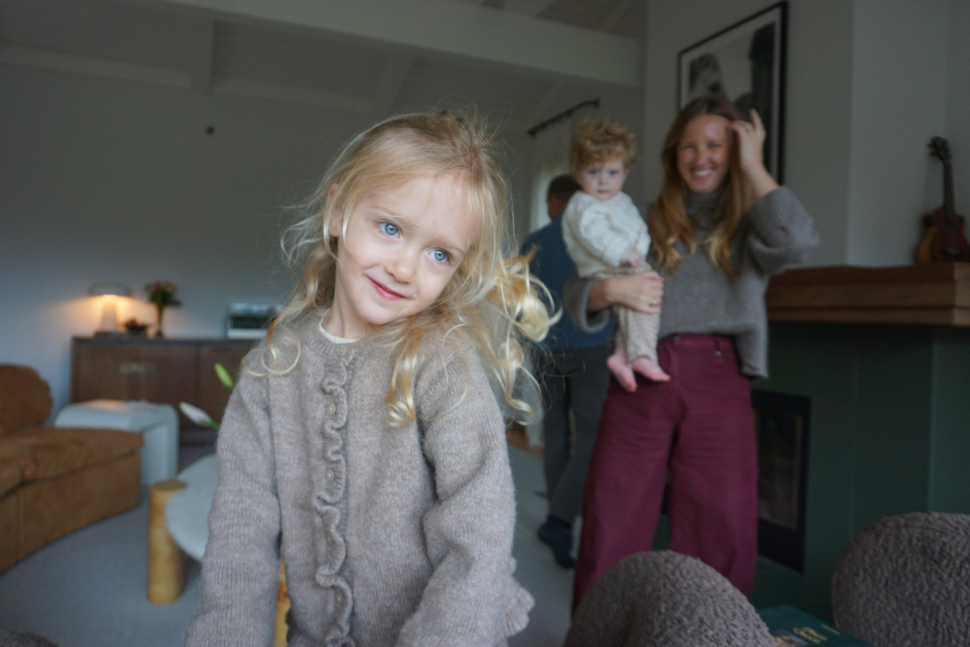 Close portrait of The Fleischmann daughter smiling with her family laughing together in the living room behind her
