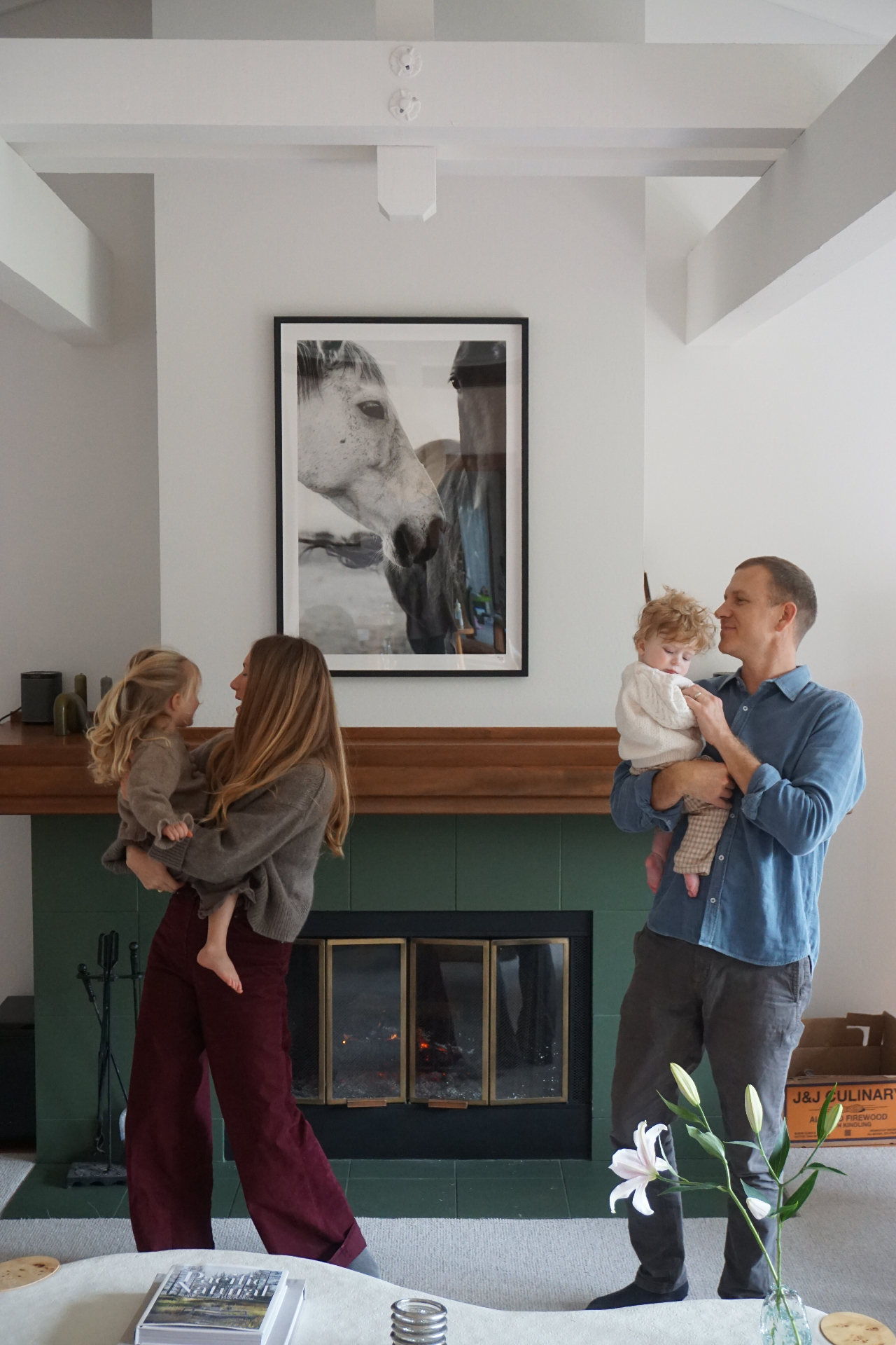 The Fleischmann parents holding their children by the fireplace beneath a framed horse photograph