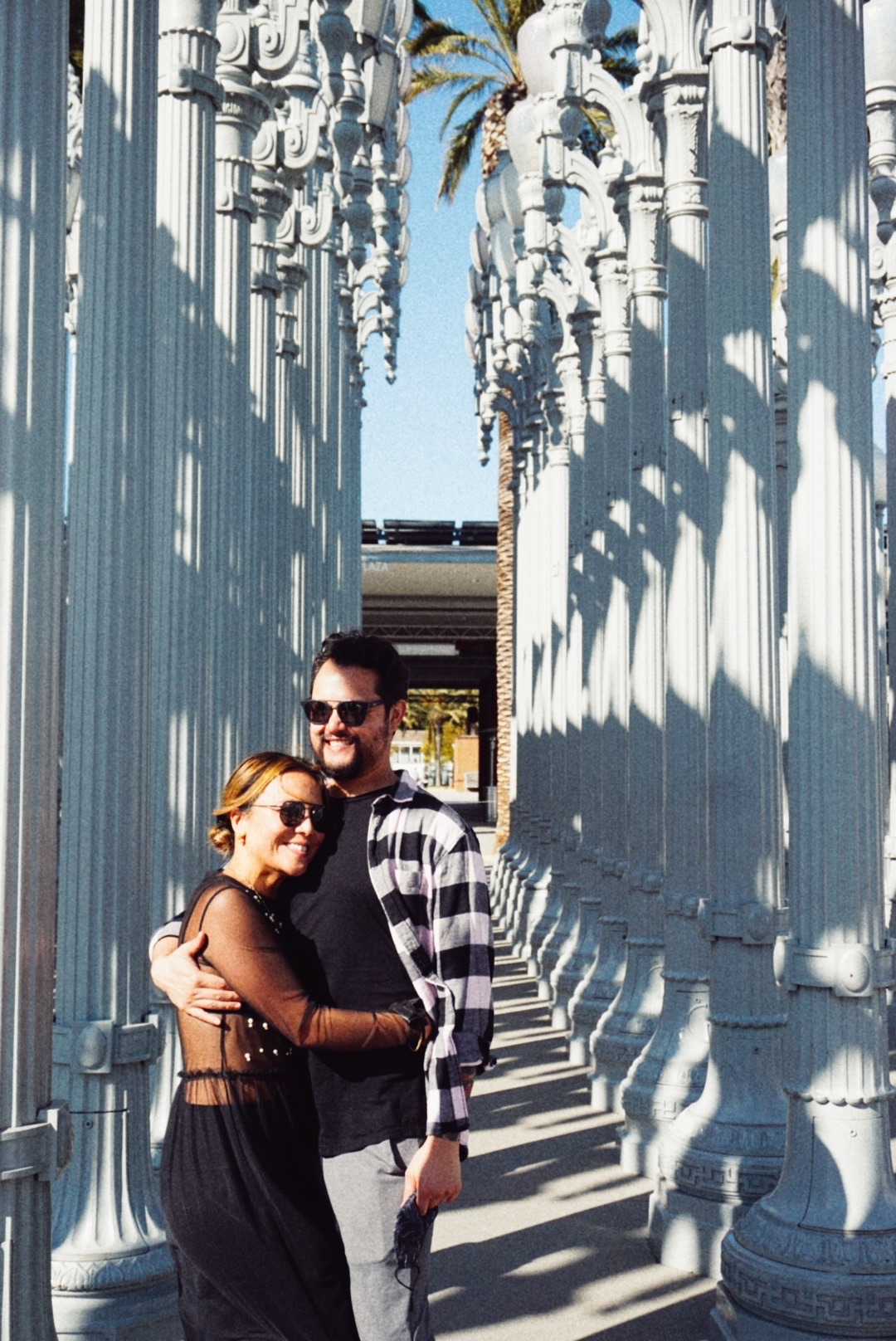 Kim and Nick embracing between white columns during their engagement session