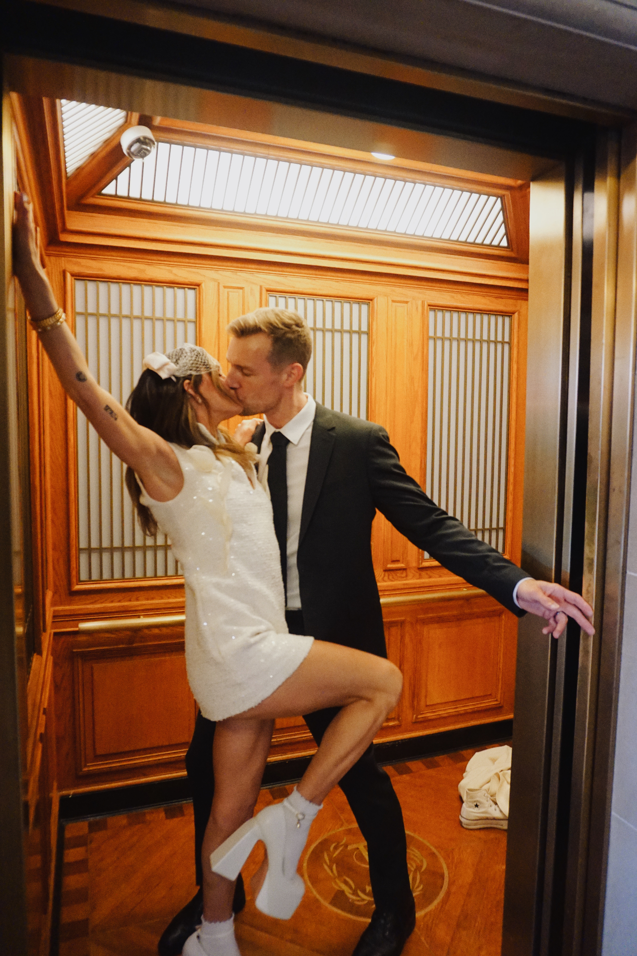 Maggie and Jono kissing in a warm wood-paneled elevator during their City Hall photoshoot