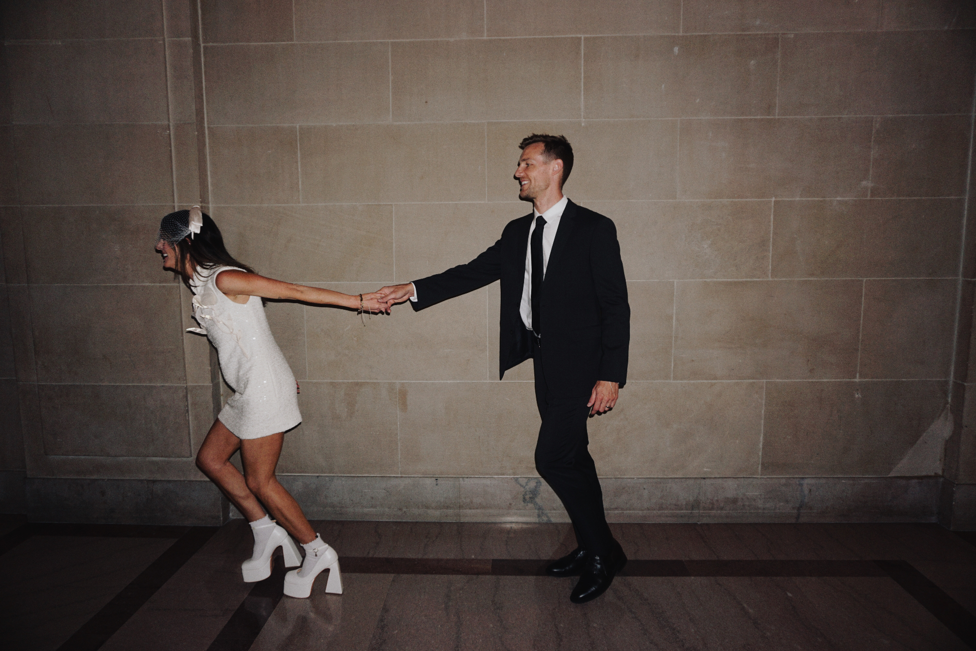 Maggie and Jono holding hands and laughing inside San Francisco City Hall