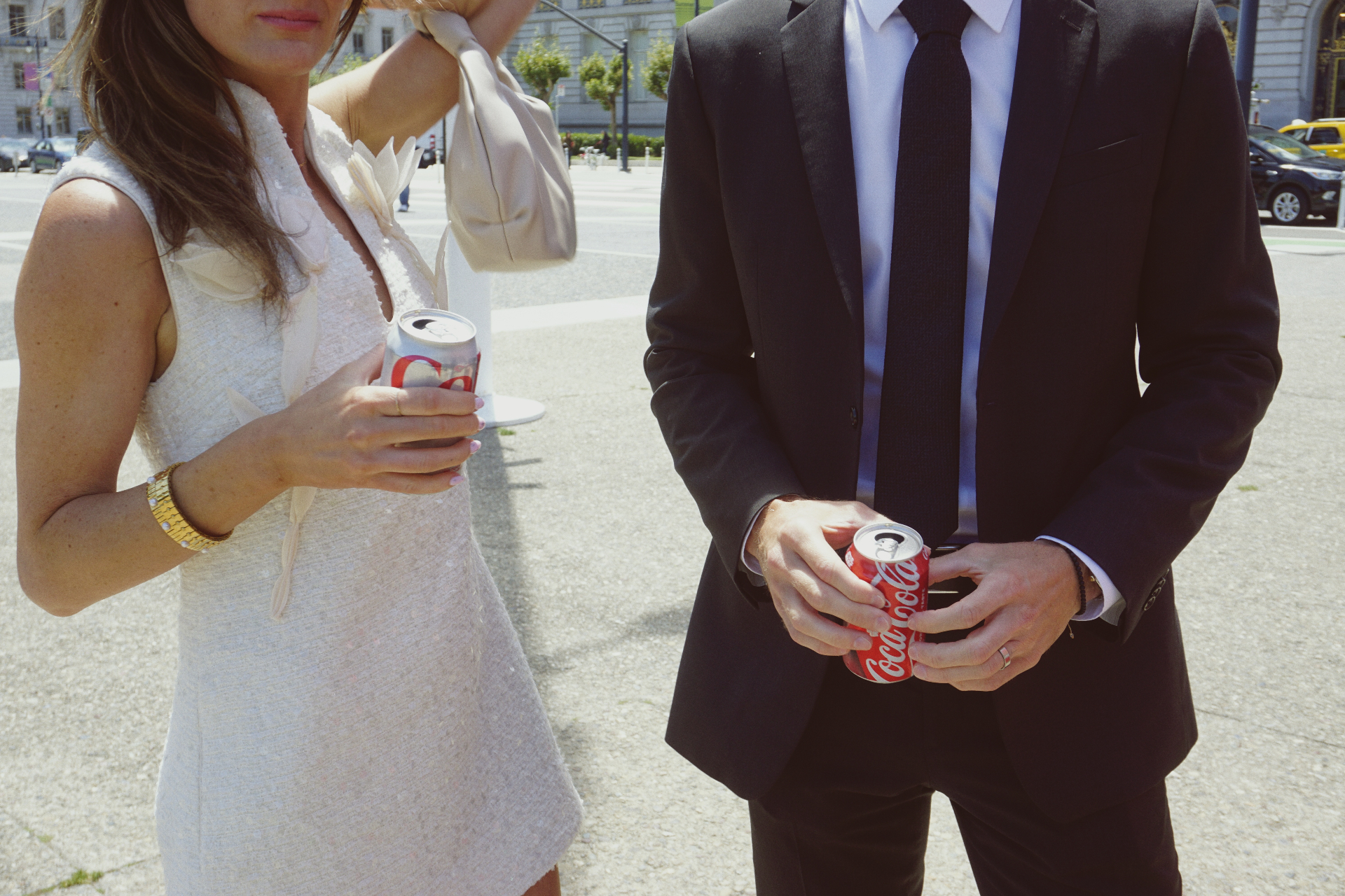 Detail of Maggie and Jono holding Coca-Cola cans in their wedding attire outside San Francisco City Hall
