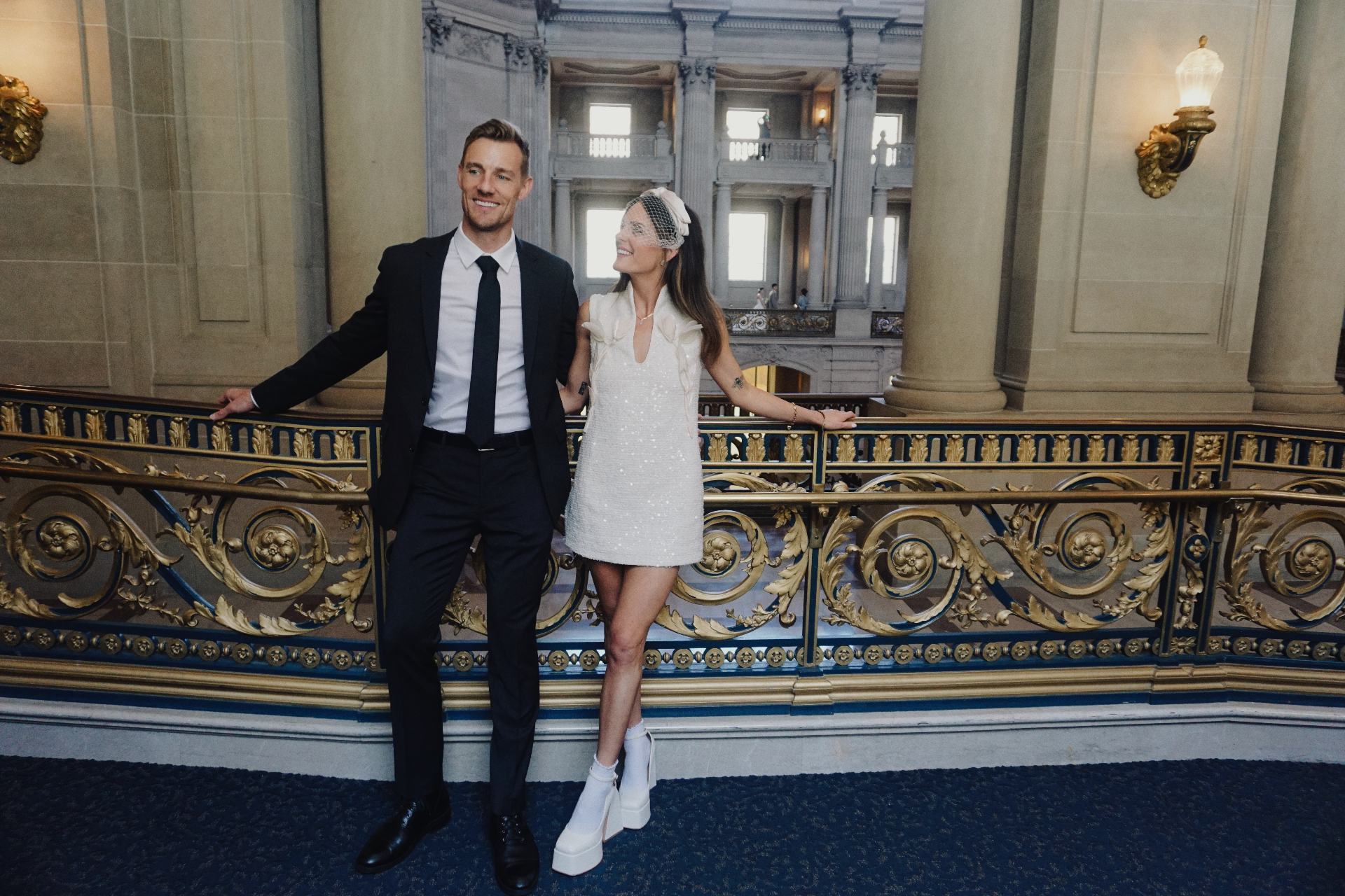Maggie and Jono leaning against an ornate gilded balustrade inside San Francisco City Hall