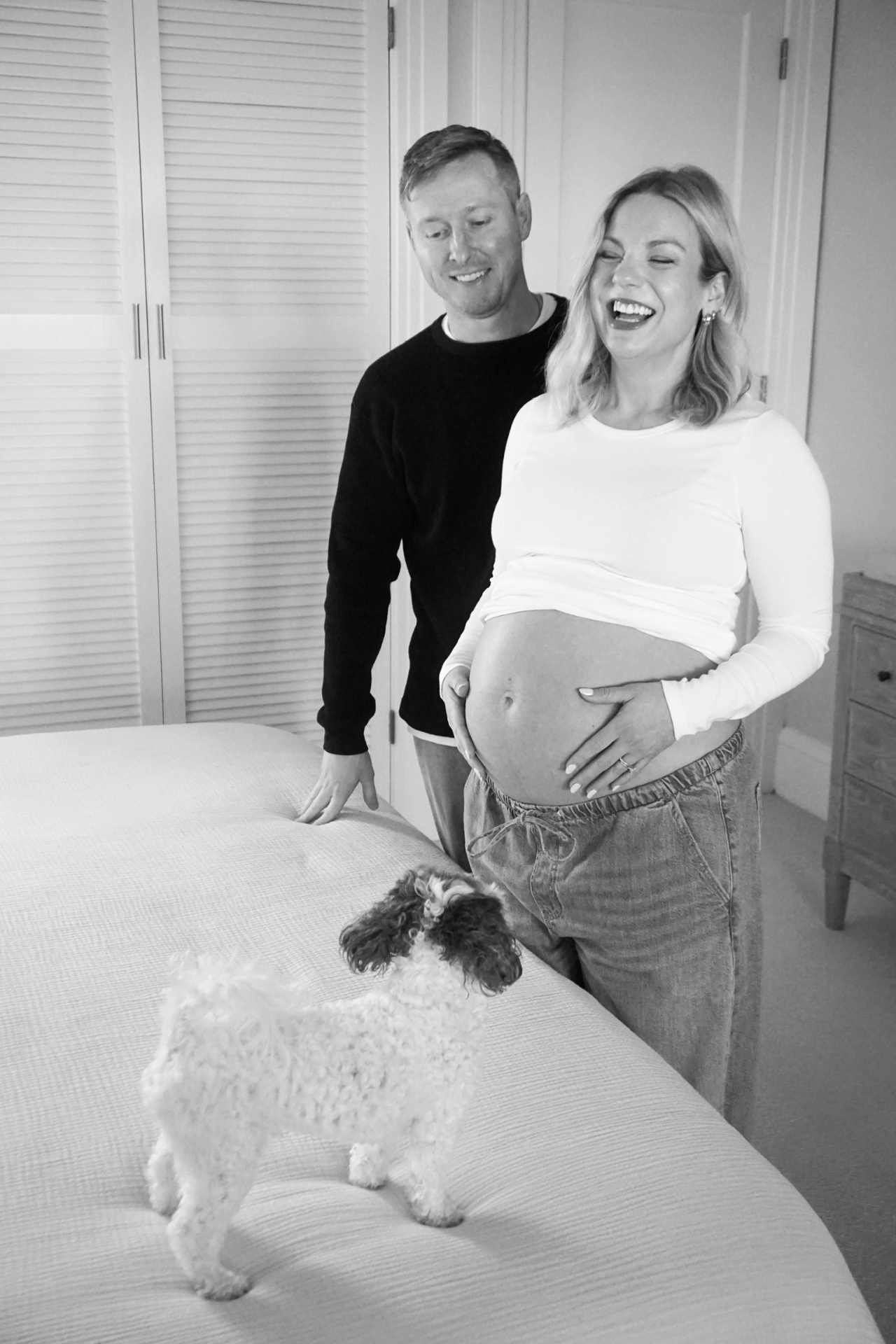 Expecting parents sharing a joyful at-home maternity moment with their dog