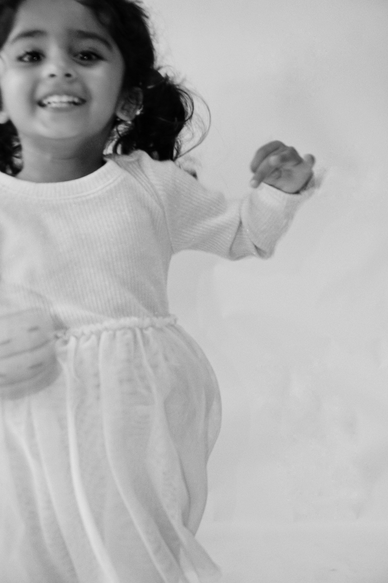 Black and white candid close-up of The Ramachandran daughter laughing mid-jump