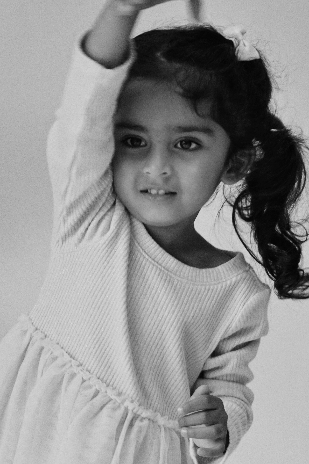 Black and white portrait of The Ramachandran daughter dancing with her arms raised above her head