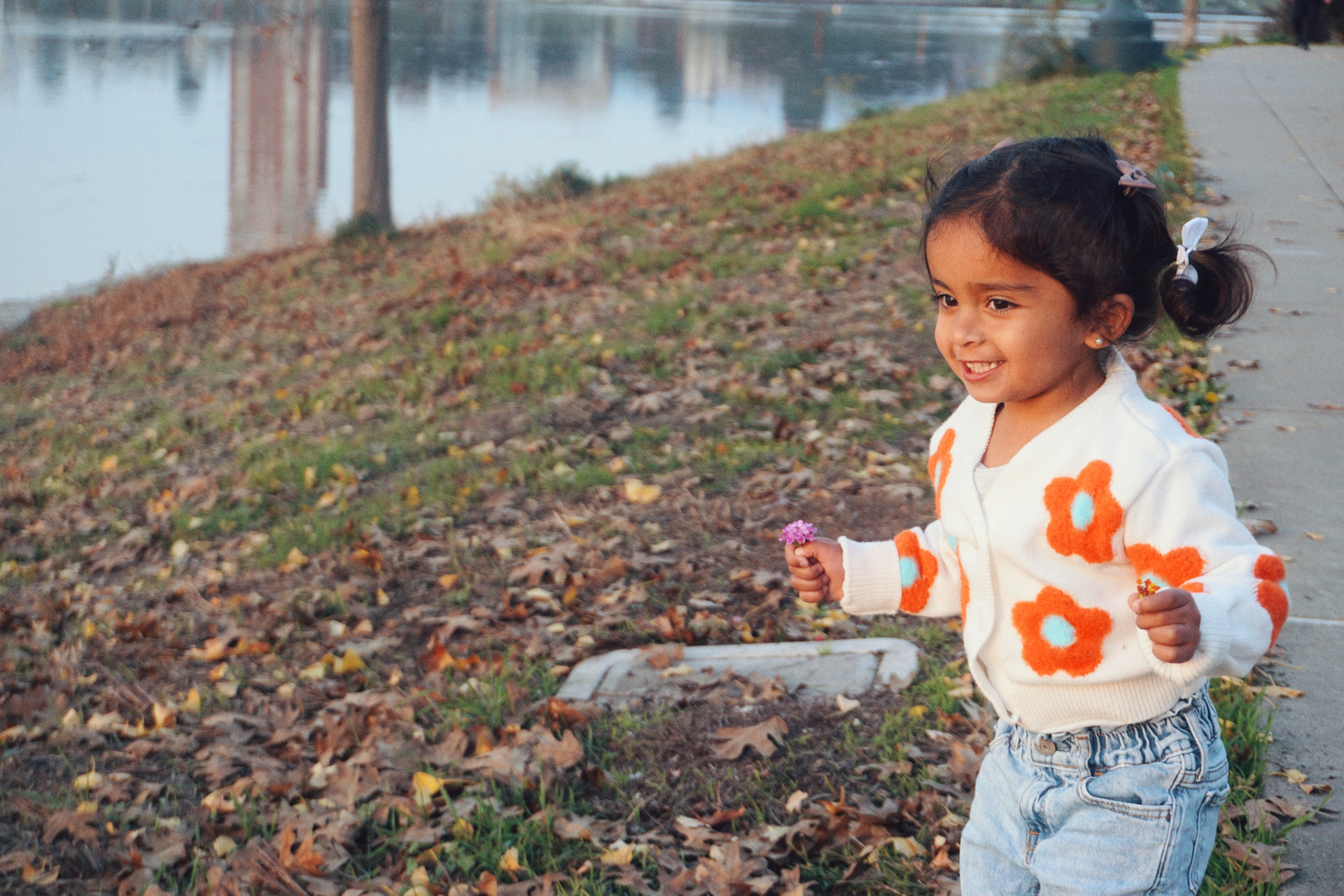 The Ramachandran daughter running along the grass by Lake Merritt holding a small purple flower