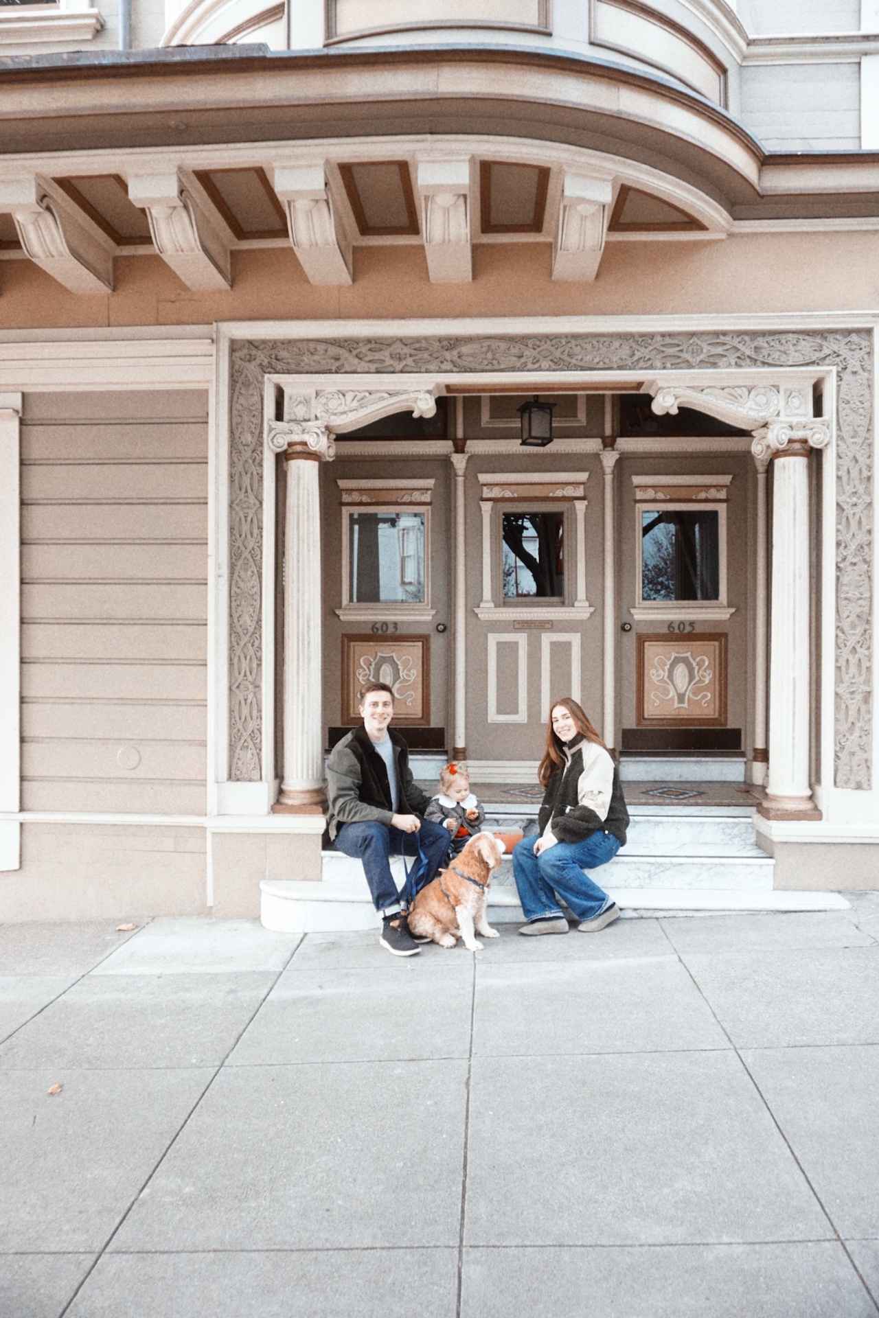The Testa family sitting on the front steps of an ornate San Francisco Victorian home with their dog