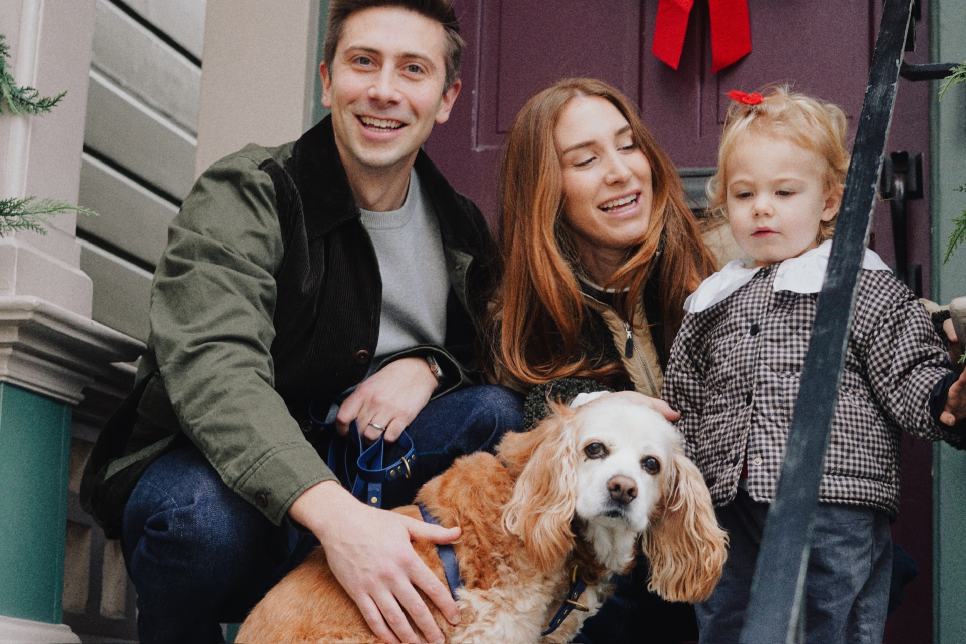 The Testa family laughing together with their cocker spaniel on a festive San Francisco doorstep