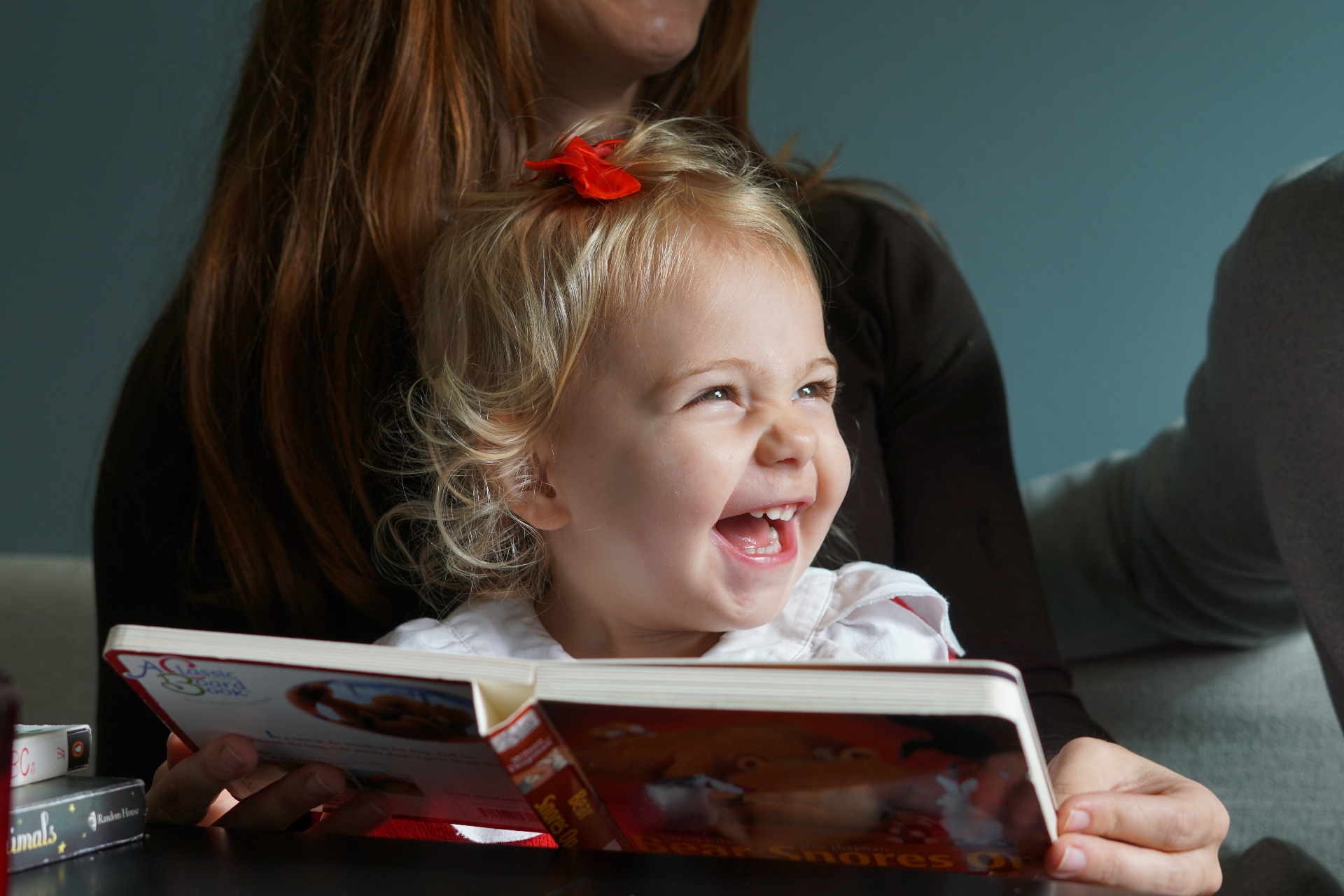 The Testa daughter giggling while reading a picture book on her mother's lap