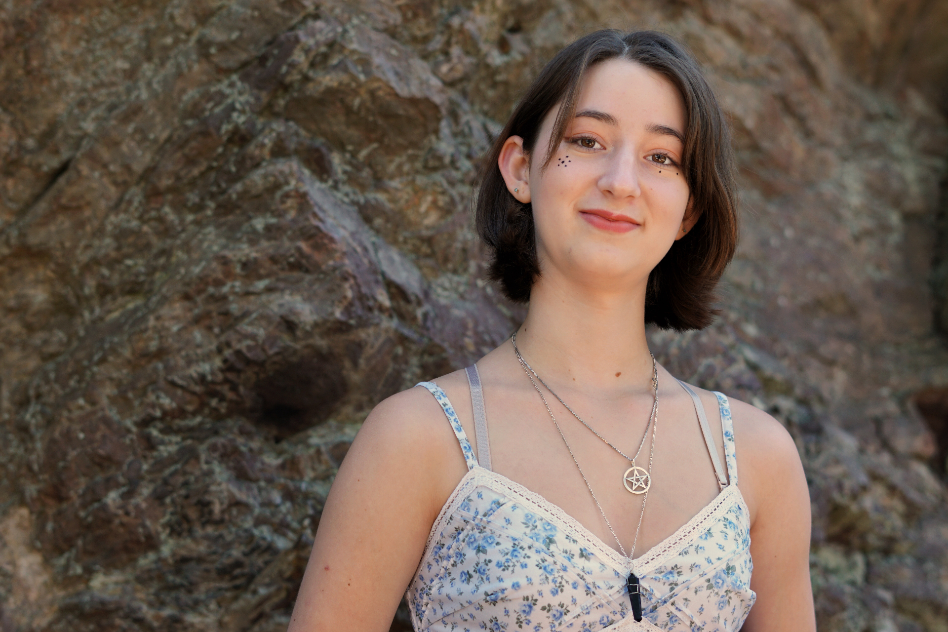 Close senior portrait of The Trimble daughter smiling in front of a textured rock wall