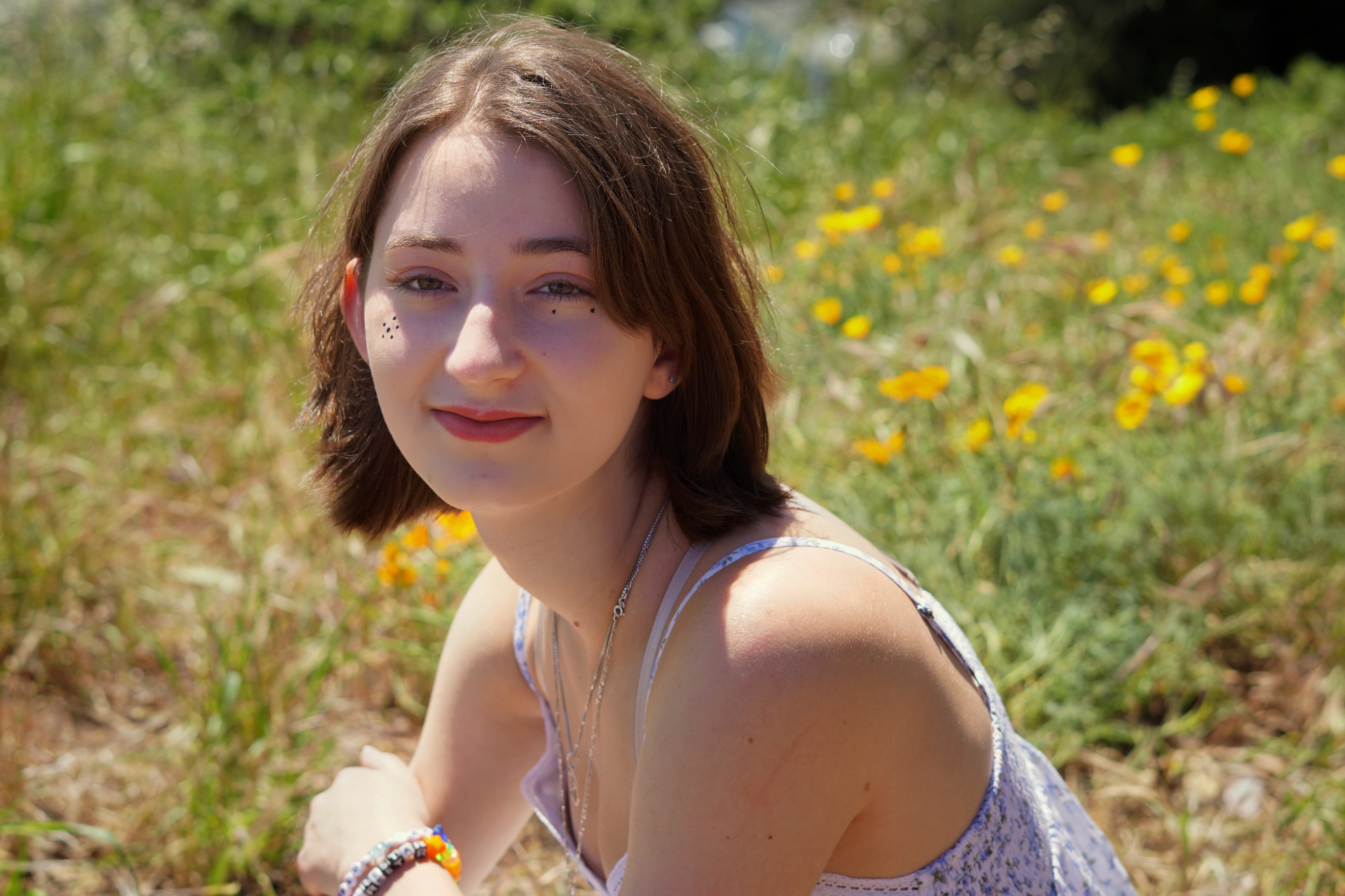 Senior portrait of The Trimble daughter in a sunlit field of yellow wildflowers